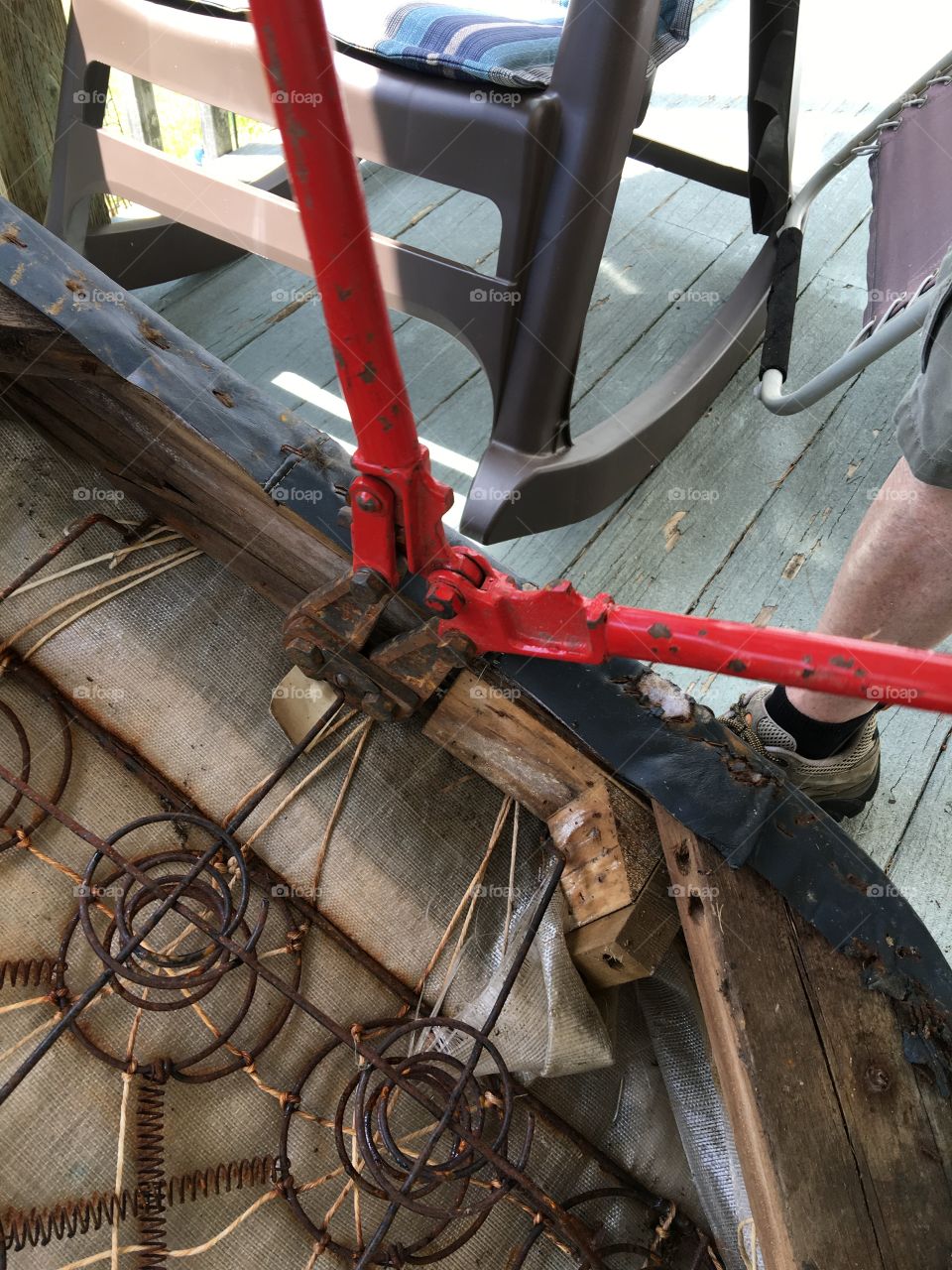 Red bolt cutters taking apart old couch.