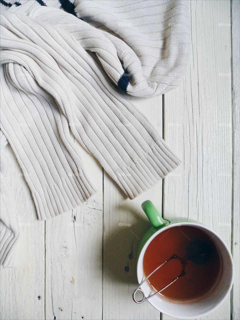 white sweater and a cup of tea on a white table