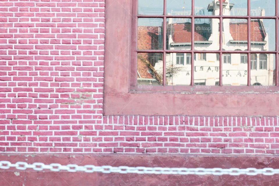 Portrait reflection of a building from the Dutch colonial heritage on a building window framed by wooden windows, namely the European-style maritime museum, Jakarta, Indonesia.