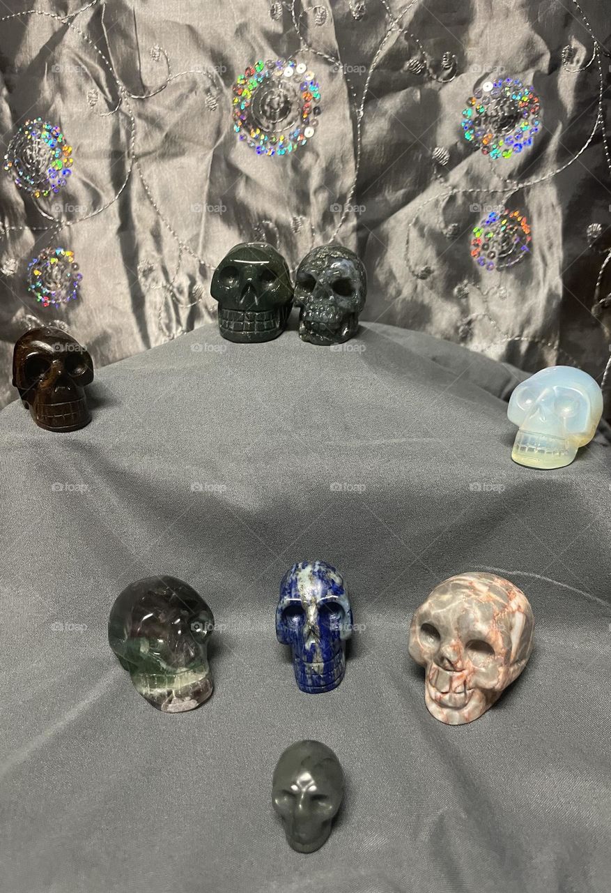 Eight beautiful crystal skulls with a glittery silver background and a grey ground.