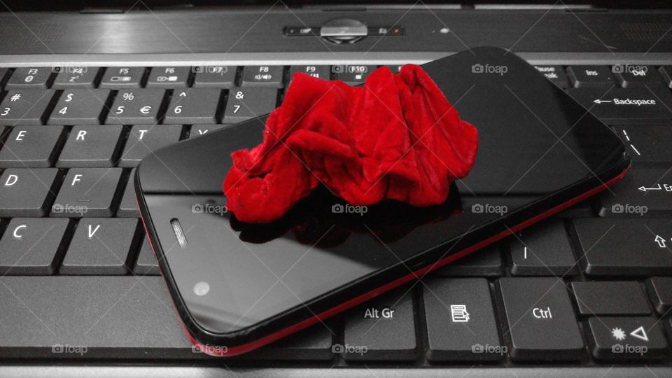 Tecido aveludado vermelho sobre um smartphone e teclado de notebook.