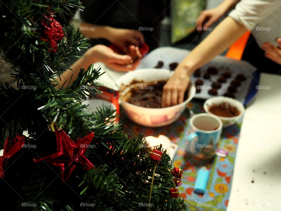 family is baking sweets for Christmas with a Christmas tree in the foreground