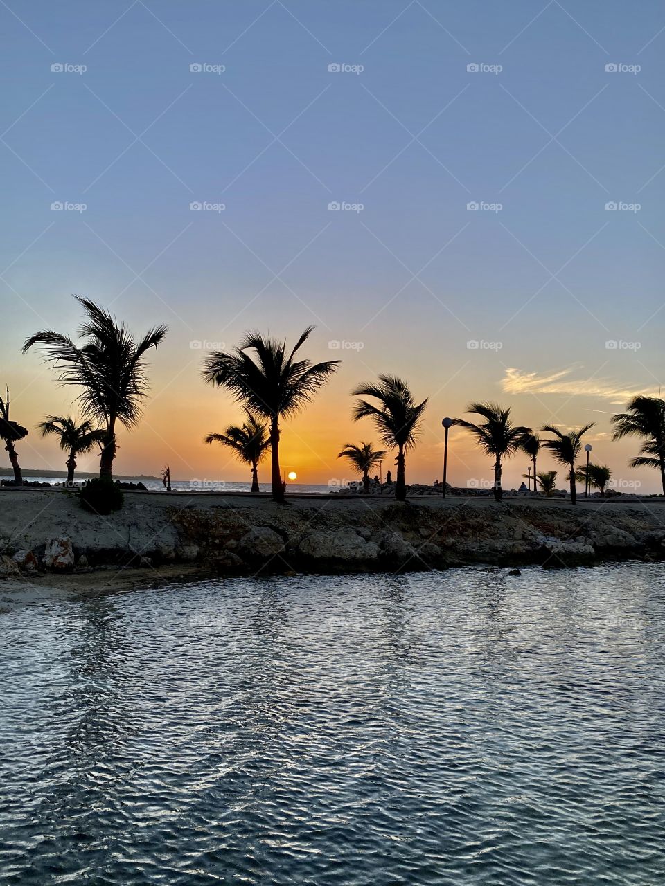Beautiful sunset in Runway Bay Jamaica with palm trees in front of it