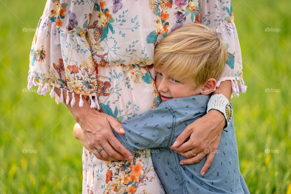 A woman with her son lovingly embraced at the field of cereals.