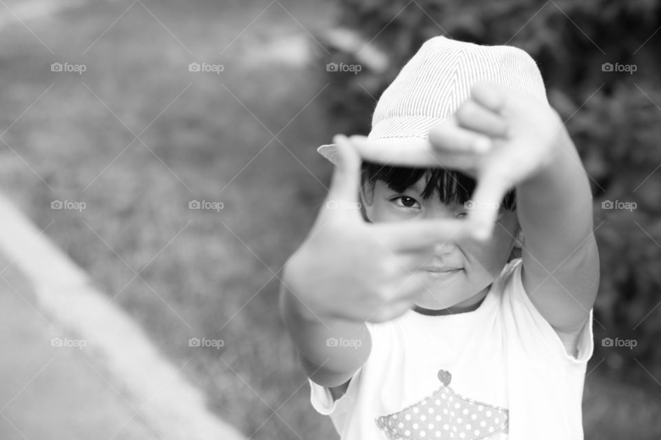 Little boy in hat looking at camera through fingers