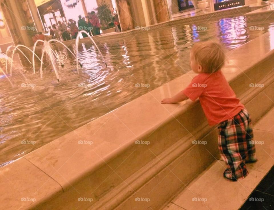 A young boy admires the water fountain in a Las Vegas hotel at nighttime. 