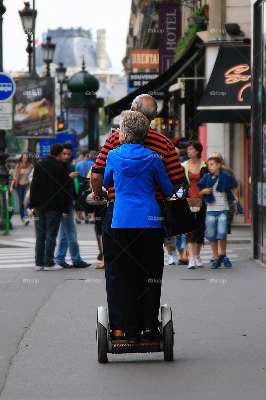 Old married couple traveling through city by segway 