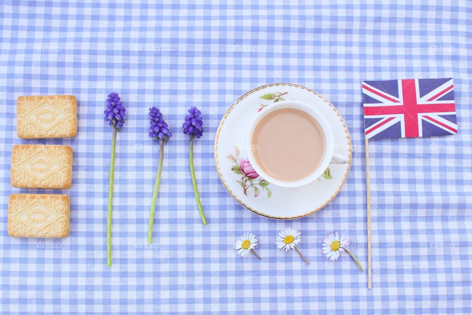 An English cup of tea with a Union Jack and biscuits on a gingham tablecloth 