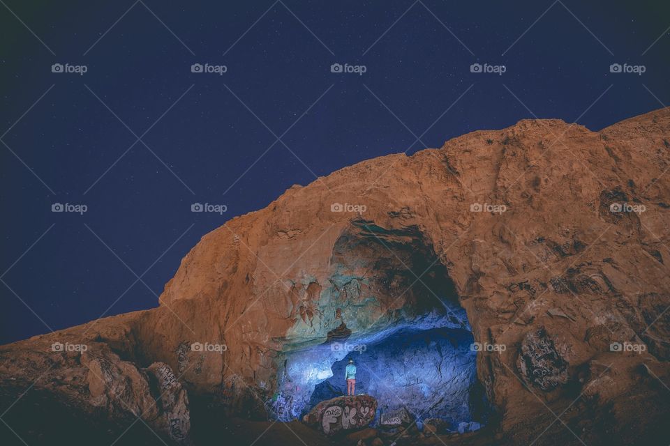 Rear view of person exploring cave in night