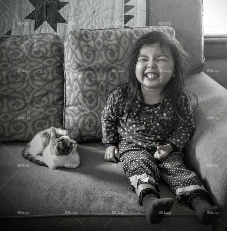 Cute girl sitting with cat on sofa