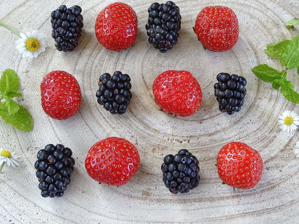 Strawberries and blackberries on a wooden background