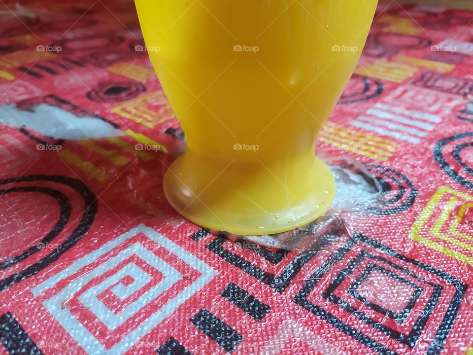 a yellow cup filled with water, on a patterned carpet