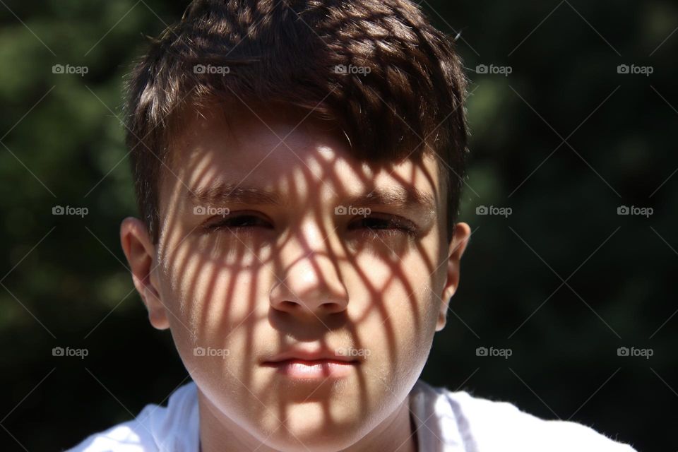 Sun shines through basket creating shadow design on face of boy