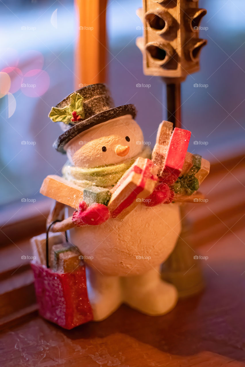 Portrait shot of the Snowman holding Christmas presents at the Street light decoration for the holidays. 
