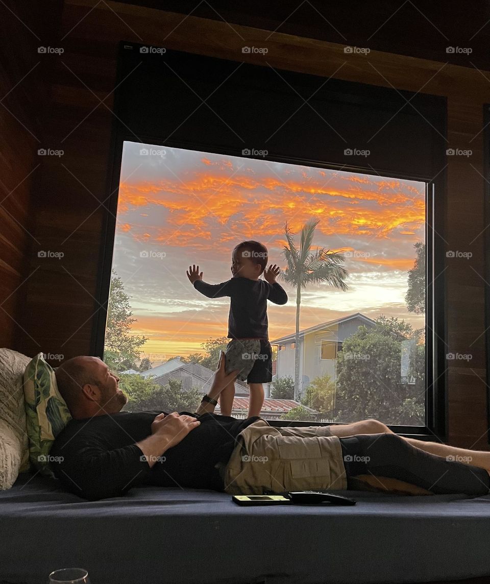 Father and son hang out near the window in the afternoon. People near the window 