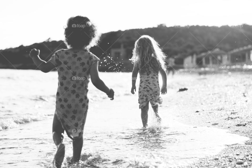 Rear view of two girls playing on the beach