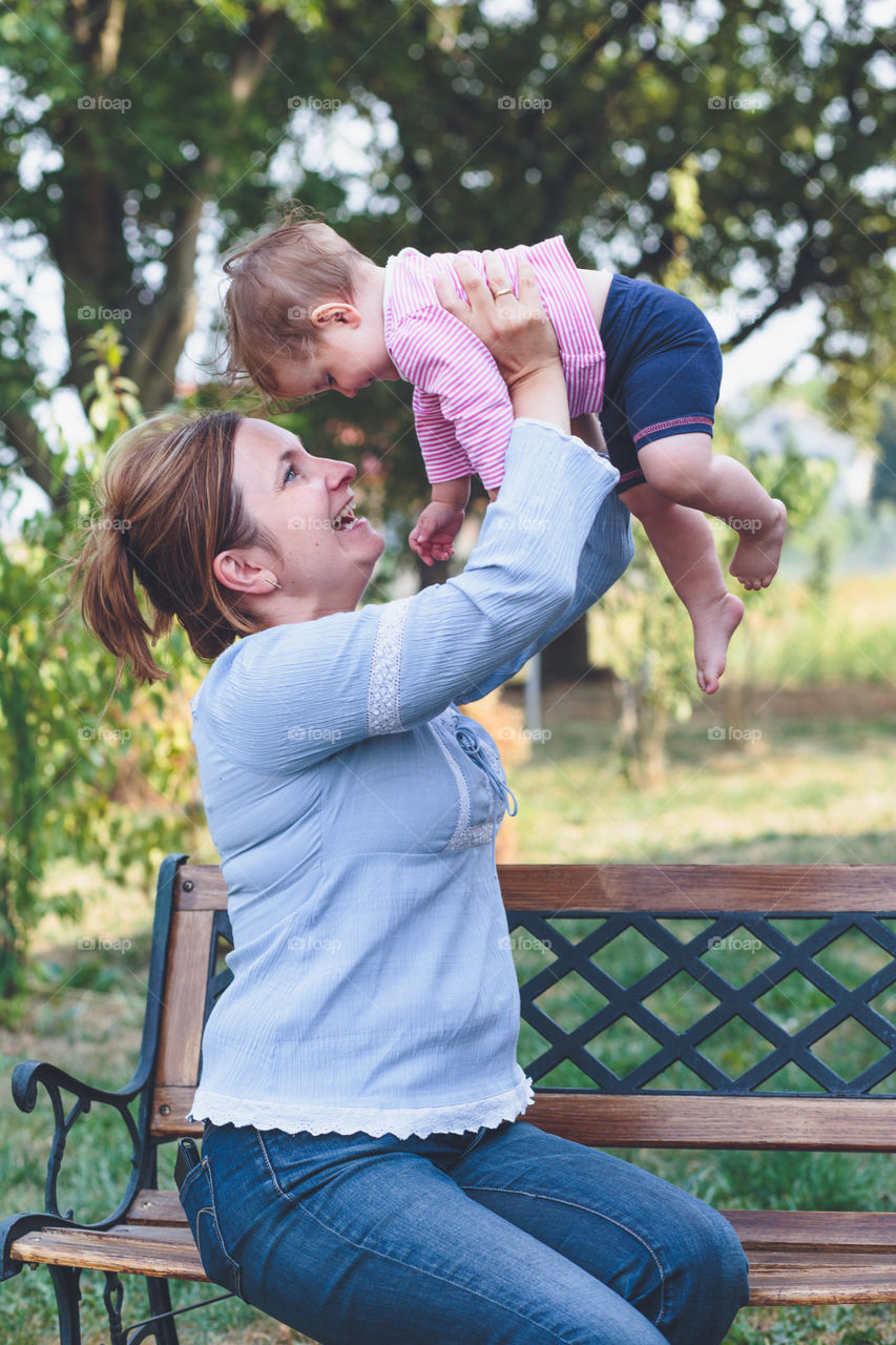 Mother carrying her son while sitting on bench