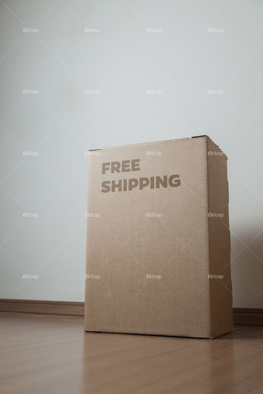 Cardboard box with written free shipping order placed on the floor in front of the house door at the time of delivery with the house door in the background. free delivery concept. transport concept.