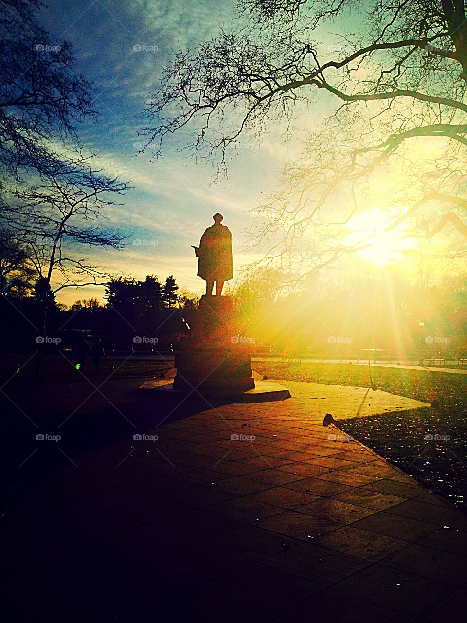 Sunset over a statue is n the park
