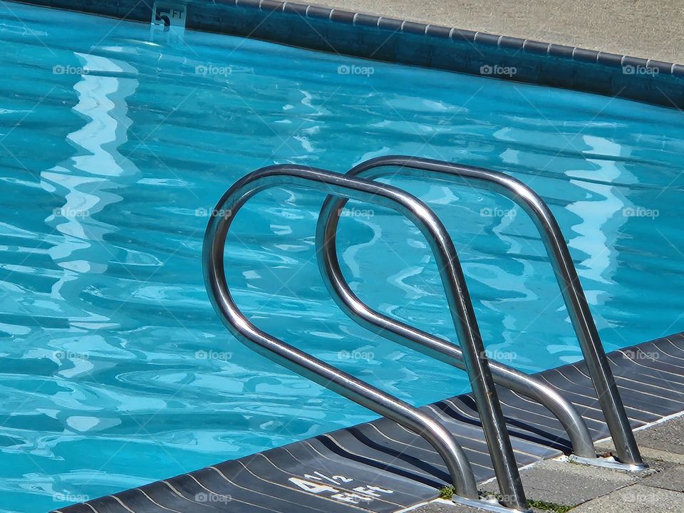 sunlight creating beautiful peaceful shimmers on the bright blue swimming pool water