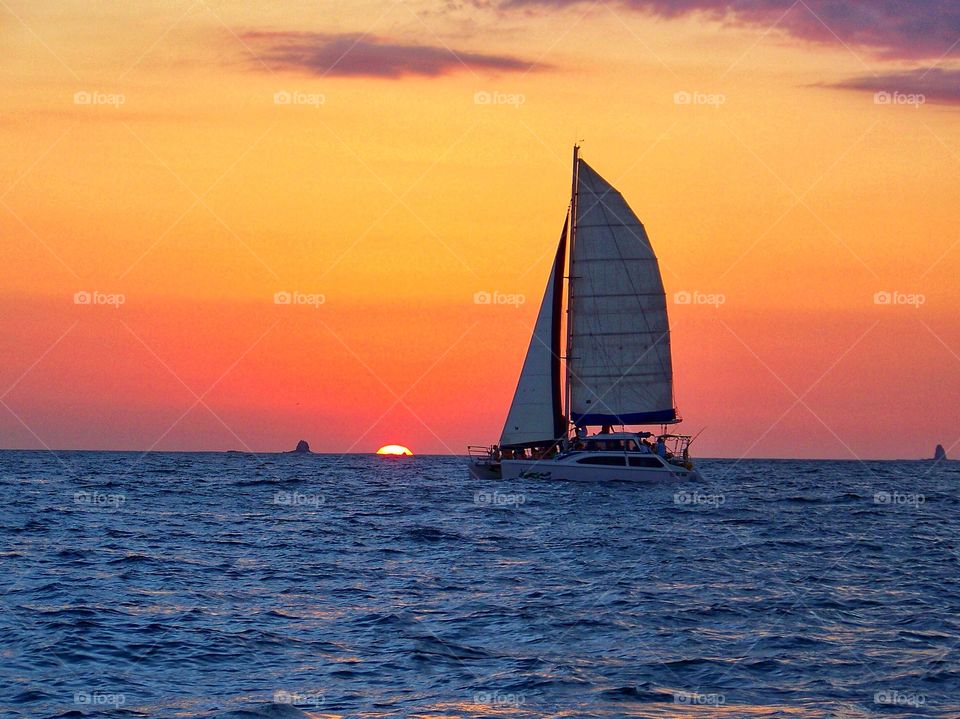 Sun setting on Costa Rica as a sail boat passes by. 