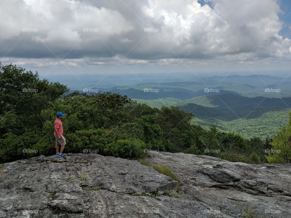 standing in the top of a massive boulder overlooking the vistas in a valley along the Blue Ridge Parkway, North Carolina.