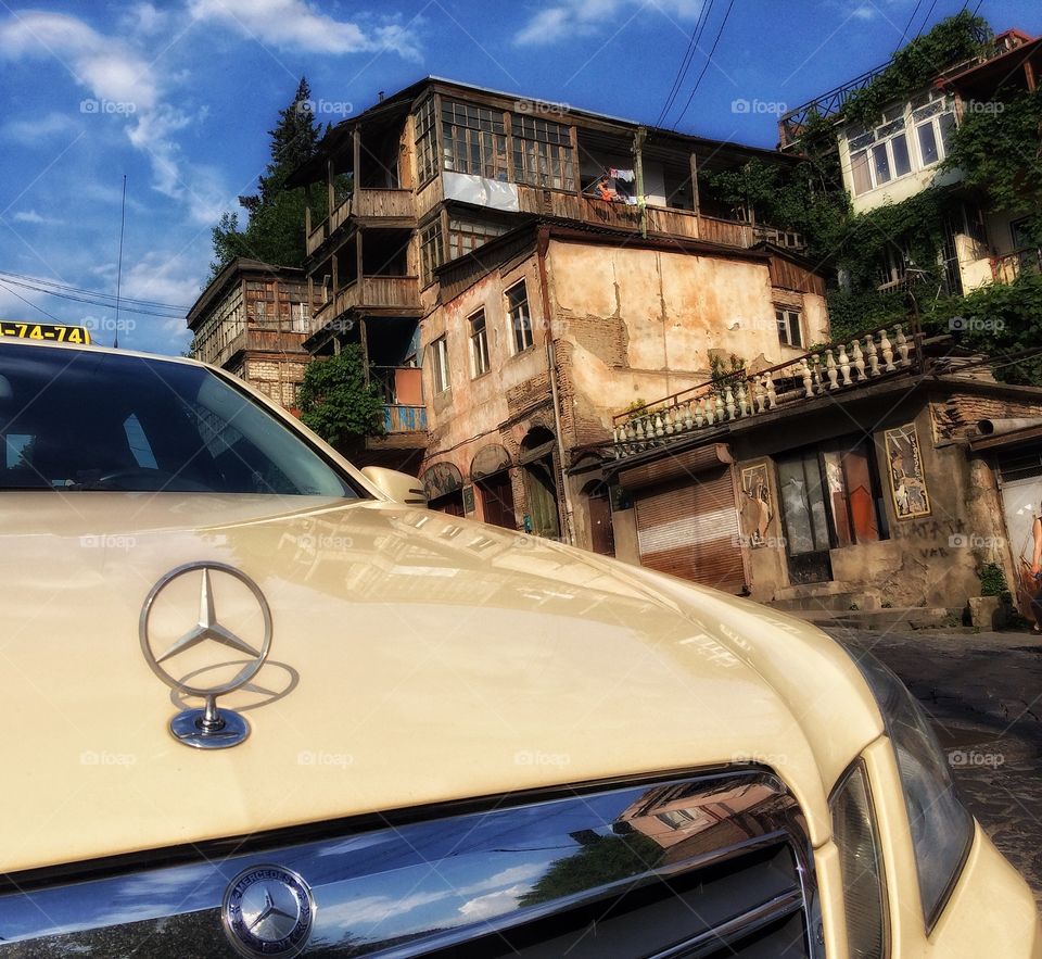 Luxury living. . This picture was taken in Tbilisi, Georgia. I was walking by an older part of the city when I saw that Mercedes taxi. I thought this composition may underline the difference of modern and old.  