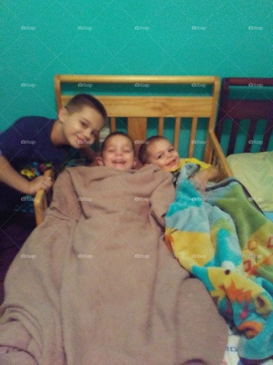 these three boys two in the bed they are sons of my son baby cheesing loving to take this picture in their room was Playing now laying down cute as a bug in a rug. Group together happy times close together these are my offspring's seed of my seed son