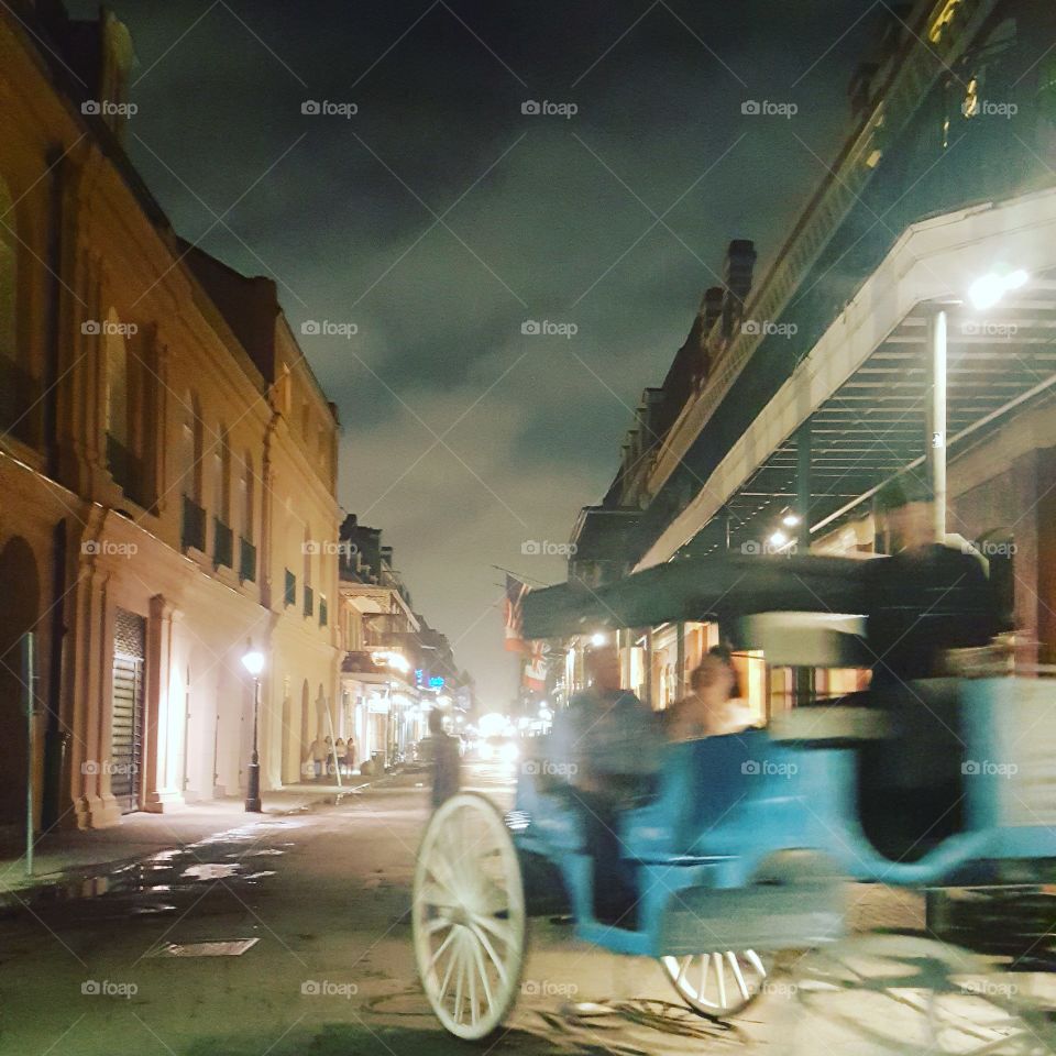 spooky night time street scene in New Orelans with a blue carriage and possible ghost