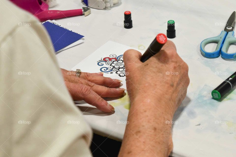 Woman's hands coloring a design