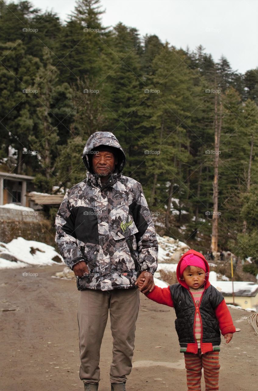 A mountain Village girl walking with his grandfather in very cold weather.
