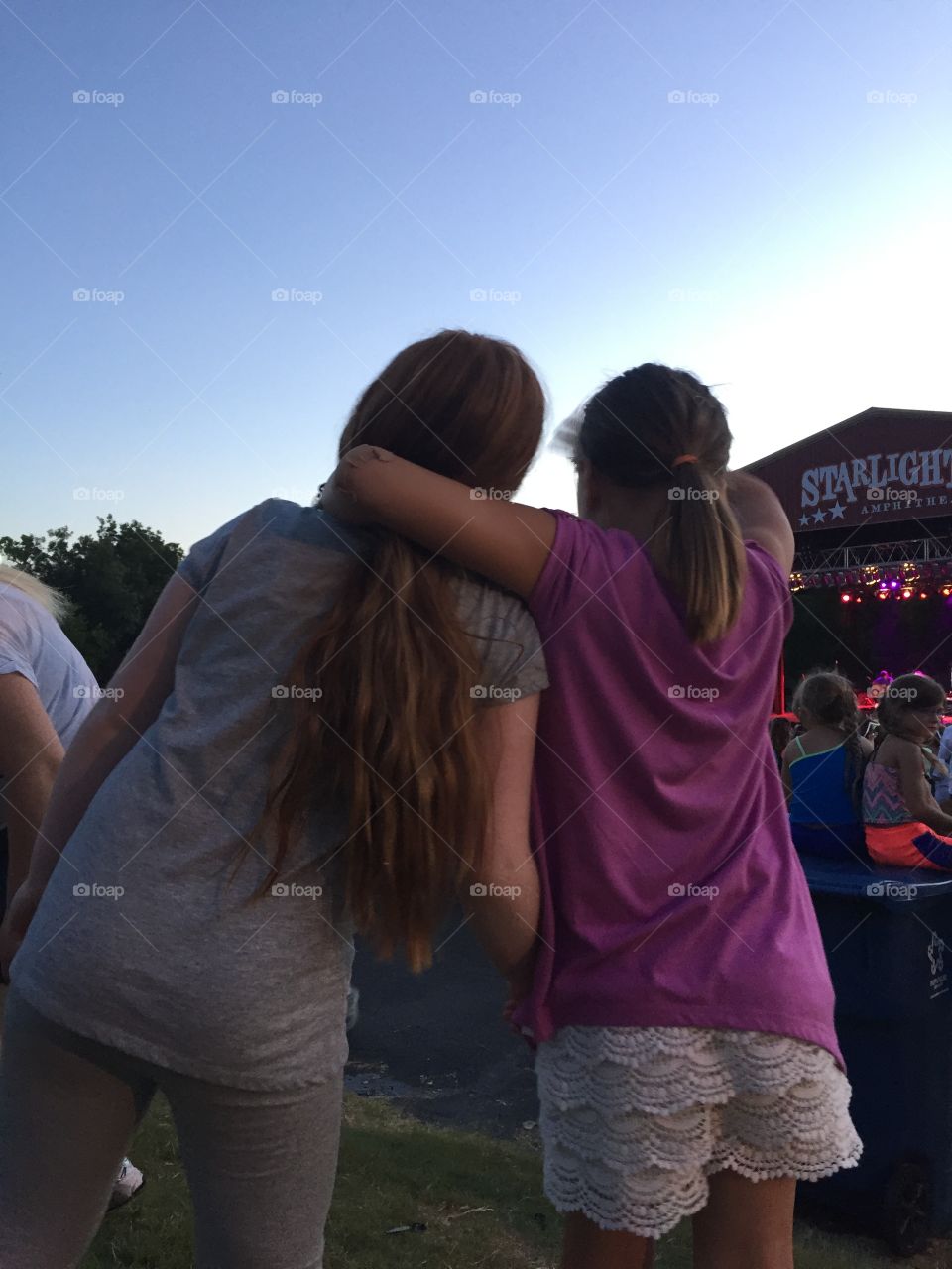 Two young girls enjoying their first outdoor concert 