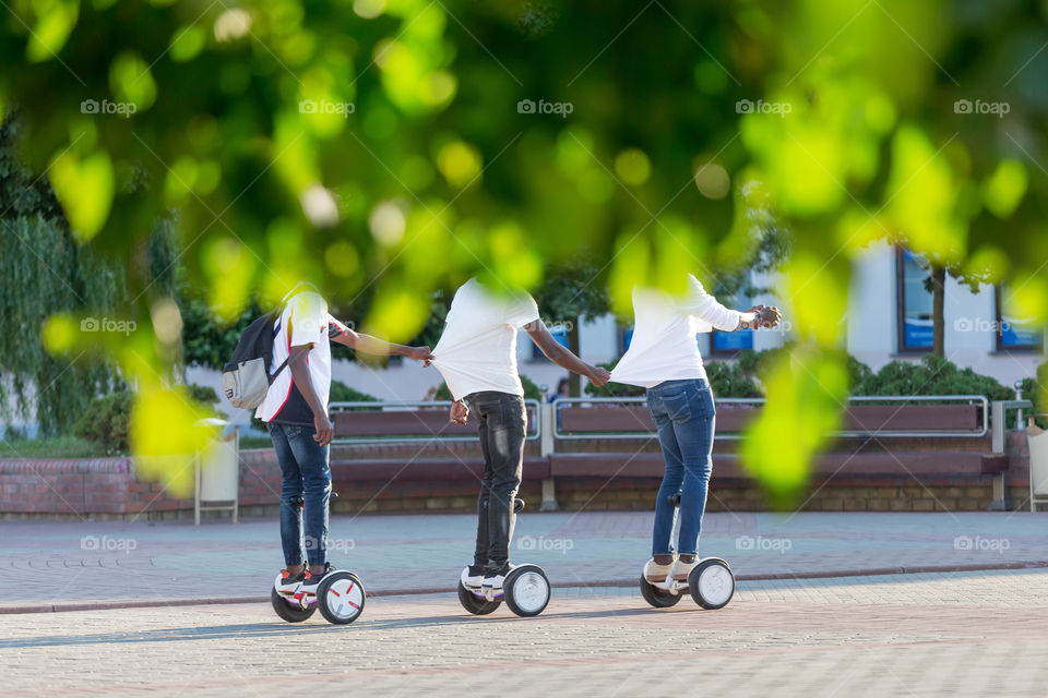 Three friends riding gyro scooters in the park, having fun time together