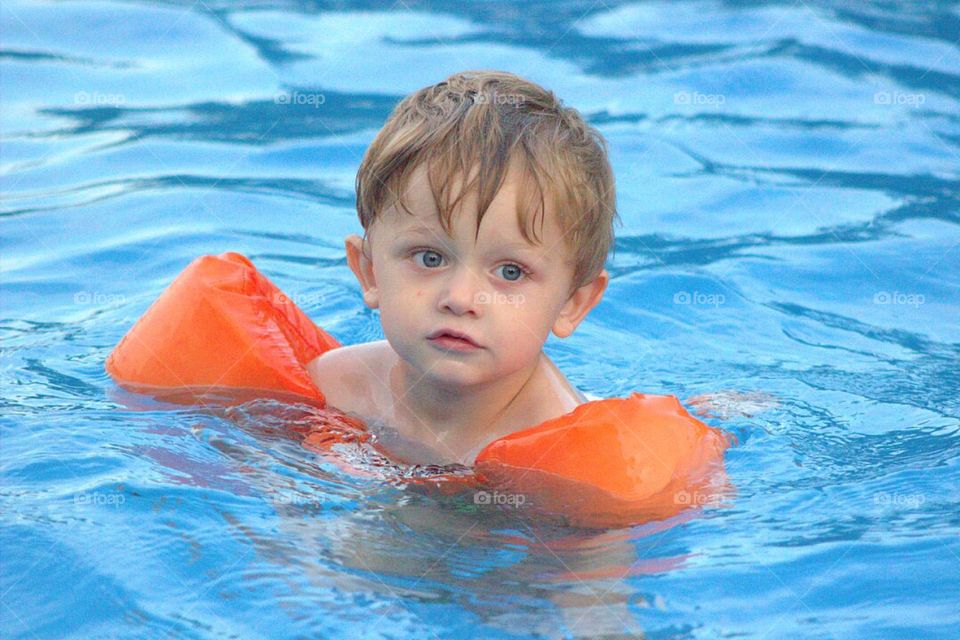 Little boy in swimming pool with life jacket