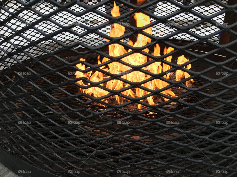 Fire pit seen through mesh fence