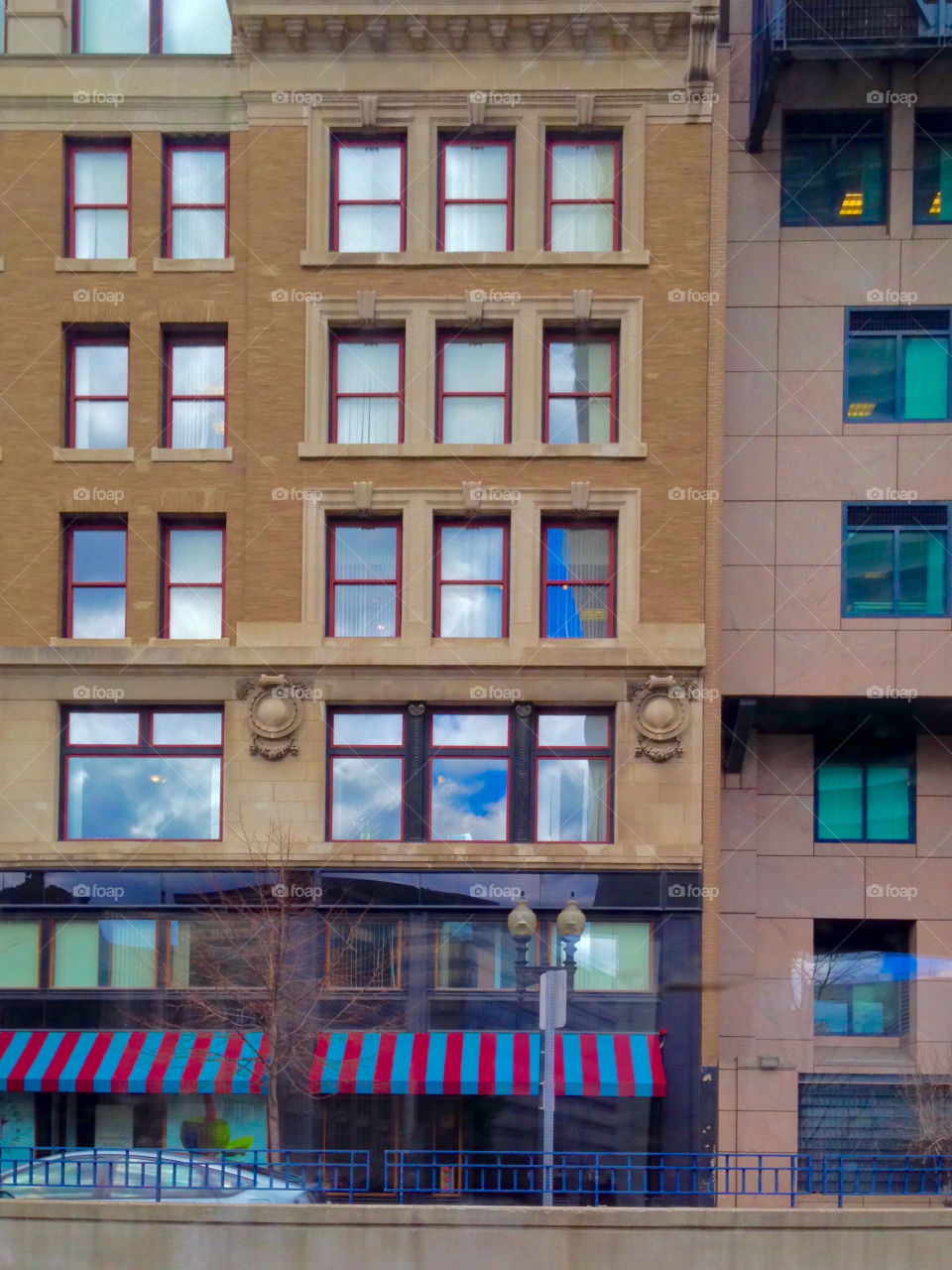 "Windows to the Sky" - front facade of building exterior with rows of windows reflecting the clouds and sky. Architectural details depict symmetry with the geometric lines, angles, squares and rectangles.