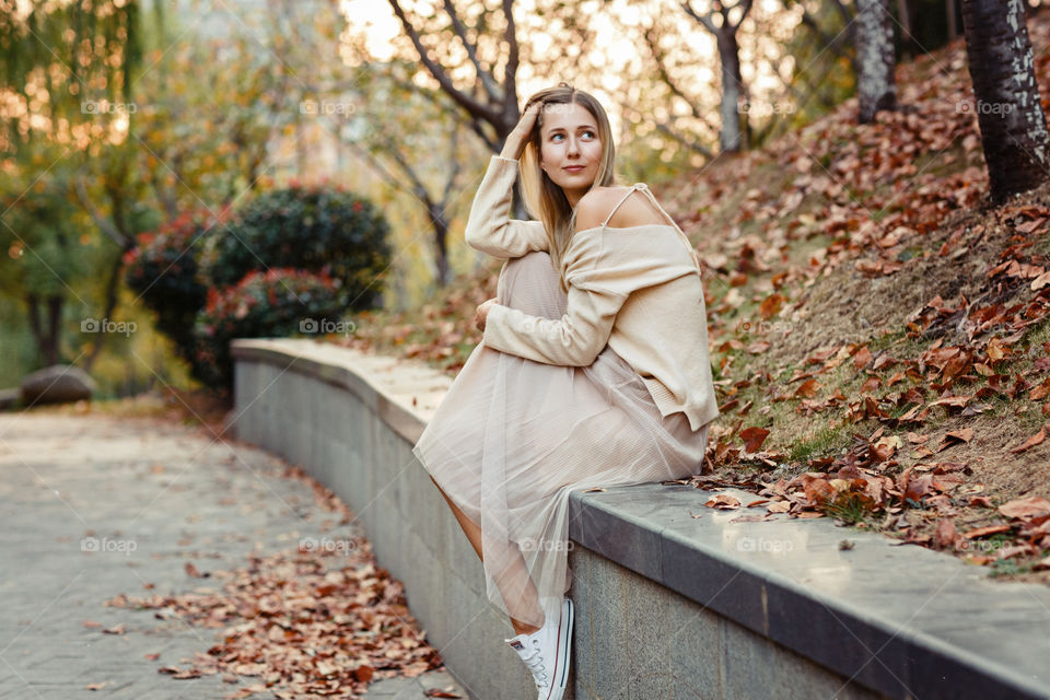 Stylish woman sitting in the autumnal park