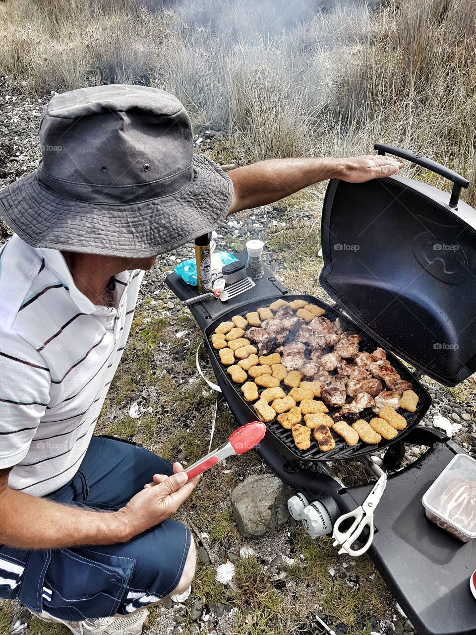 BBQ grill up at the beach summer food man with sun hat