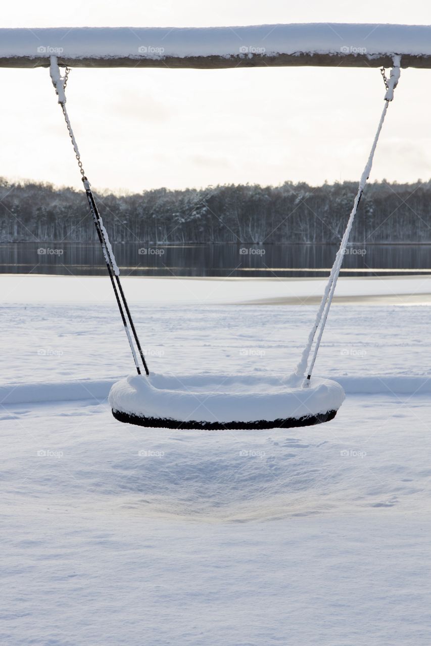 Snowy swing by the lake in winter wonderland at sunset - Vinter, gunga vid sjö täckt med snö vid solnedgång 