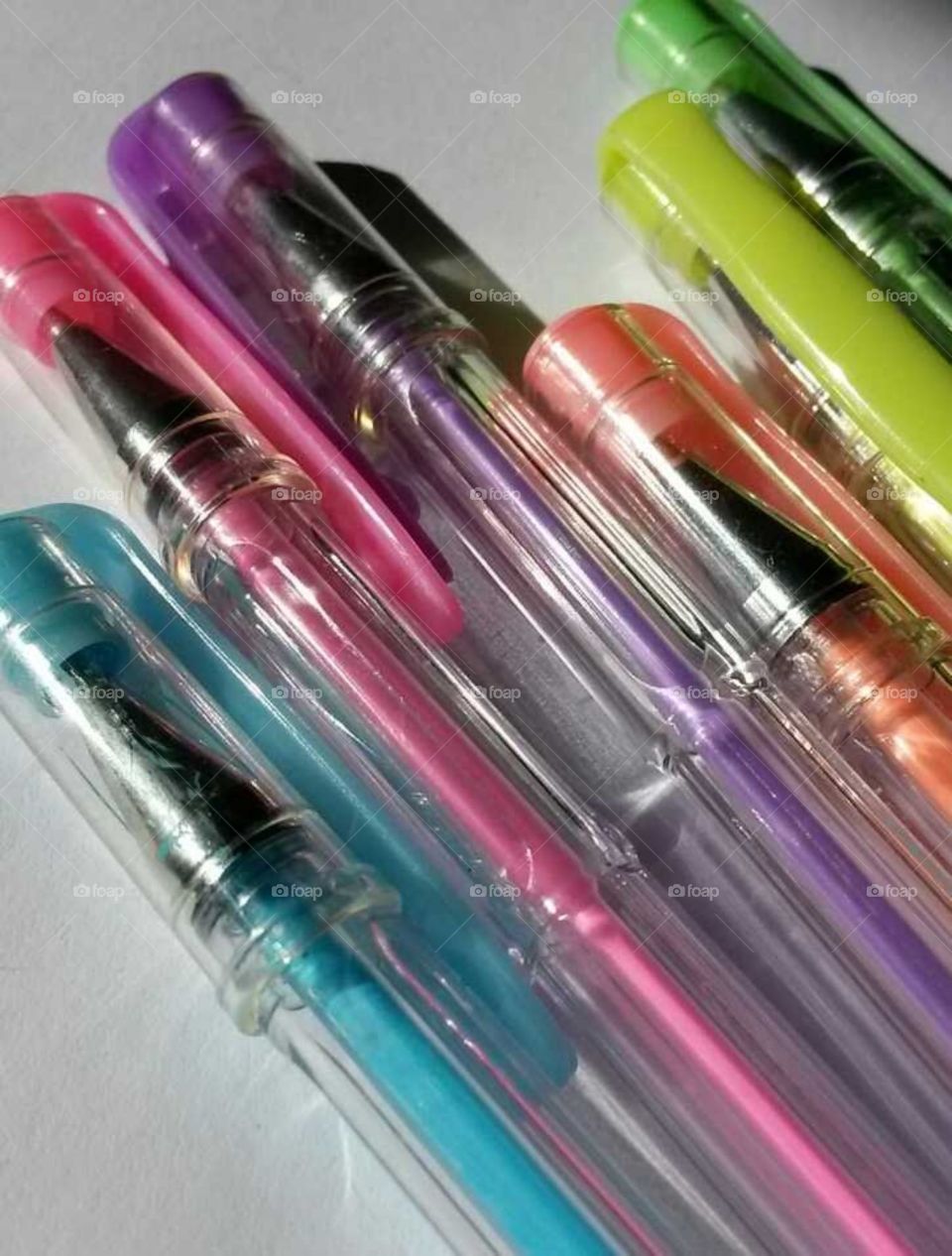 a closeup of different coloured gel ballpoint pens laying side by side next to one another