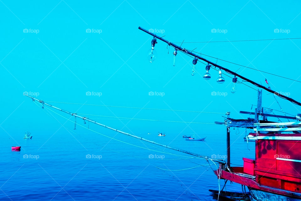 Isolated red fishing boat anchored at dockyard.