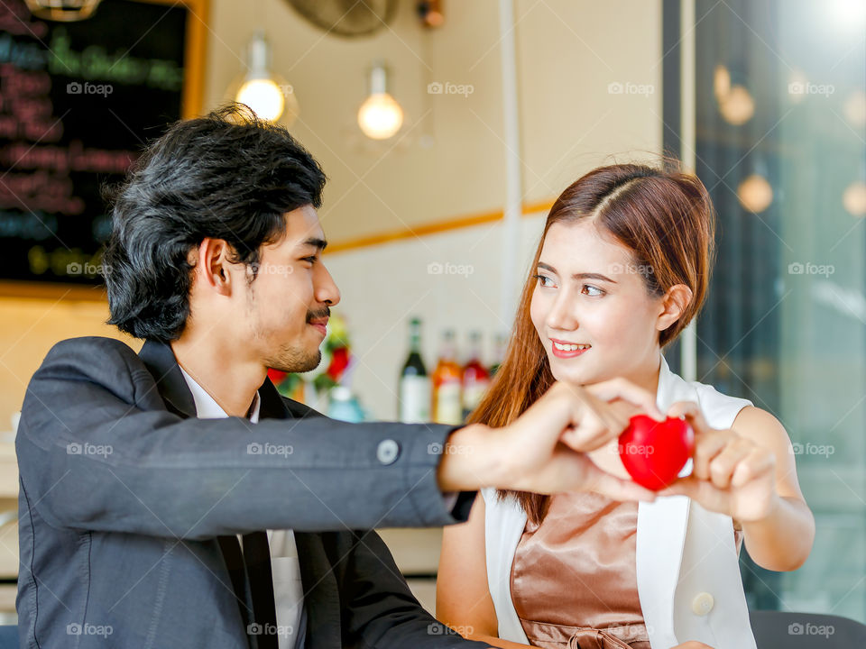 Close-up of a happy young couple holding red heart