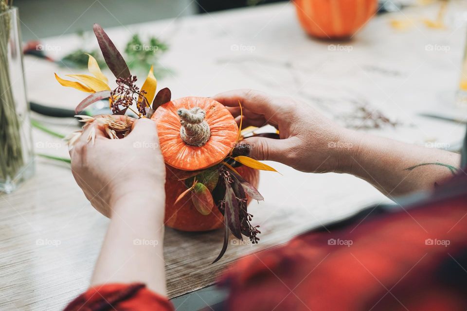 DIY autumn flower arrangement bouquet in pumpkin, florist at work, floristry studio