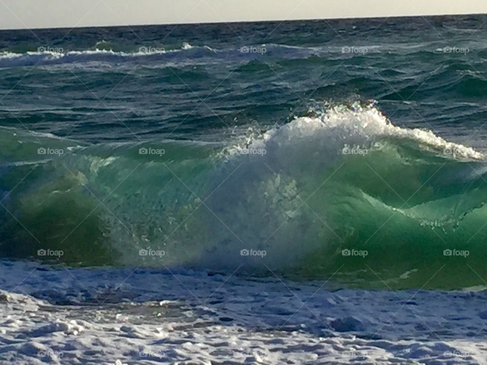 Emerald green waves crashing against the shore at Oceanridge FL