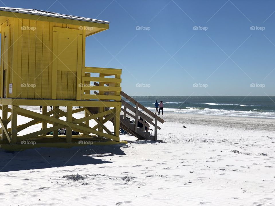 Yellow lifeguard stand watching beach goers