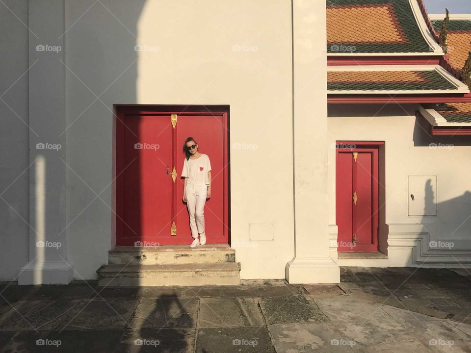 A girl standing next to a red door