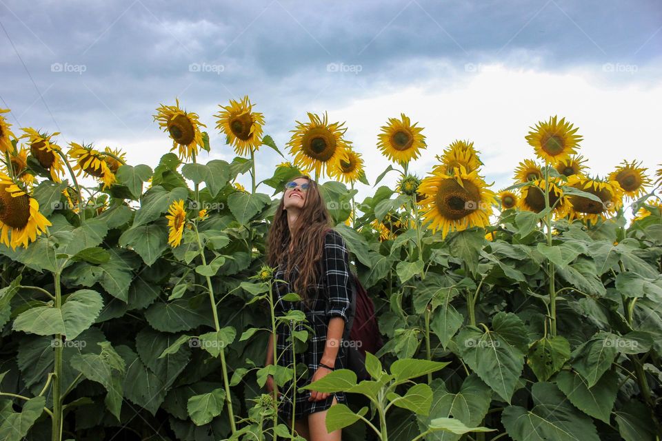 the girl stands among the sunflowers in the field
