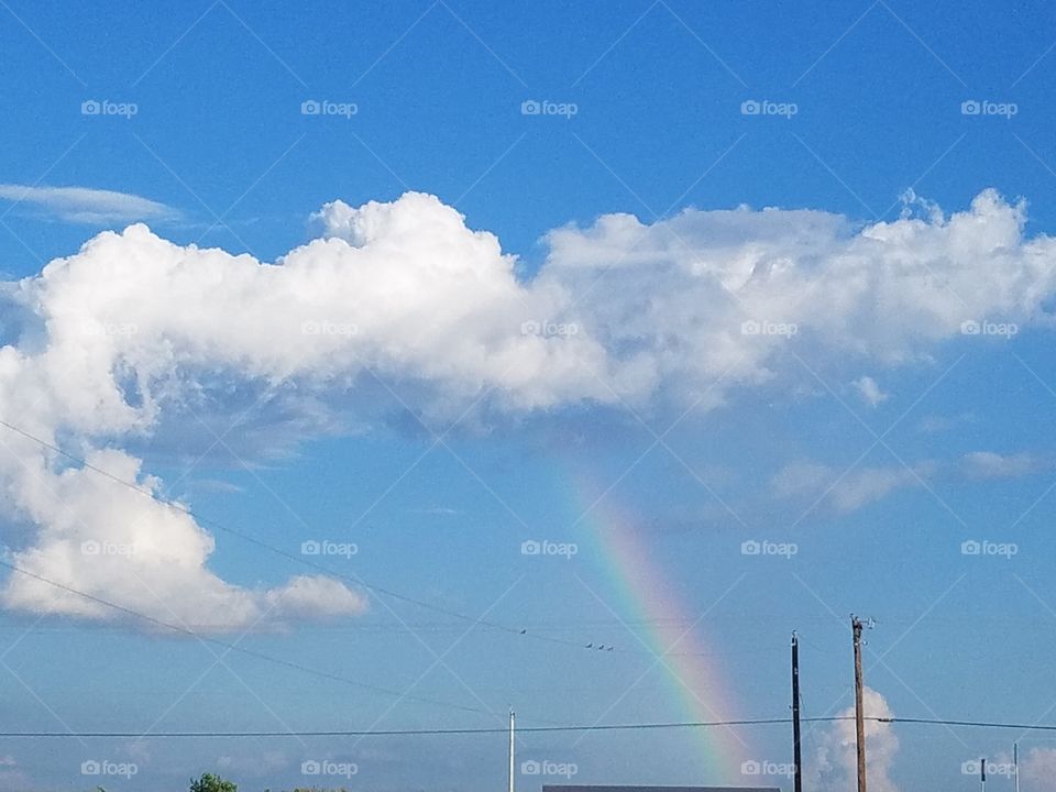 This was a rare sight as we watched the cloud dissipate & form this beautiful rainbow in minutes. This was in Copperas Cove, Texas. We were en route home & had to find a clearing to snap a quick picture before it totally disappeared. Started as one big really thick white cotton ball shaped cloud. I noticed as we drove along that in less than 5 mins from when I first noticed the dense cloud, it had dissipated from the bottom up & this pretty rainbow appeared. Can still see the horizontal 'L' shaped cloud that was remaining in the moment I took this picture.  Very cool to see. The picture does not show the true awesomeness of being witness to this but it does indeed capture our memory.