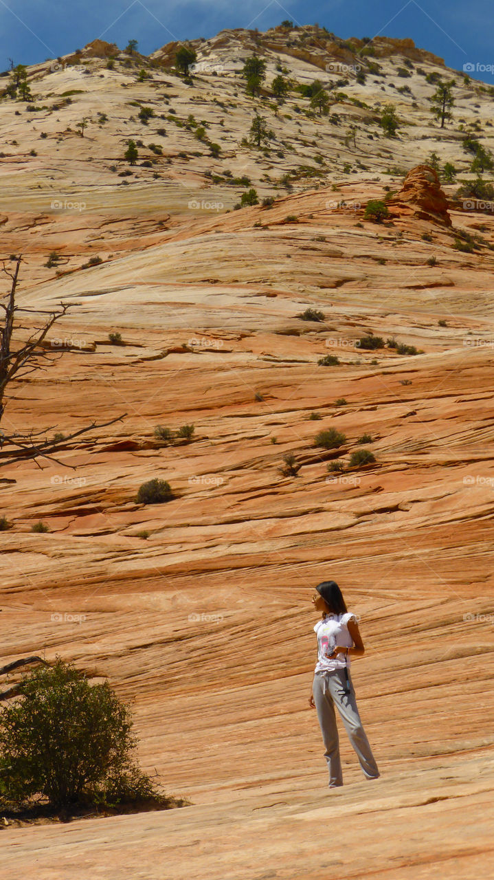 Young woman standing in front of rocky mountain