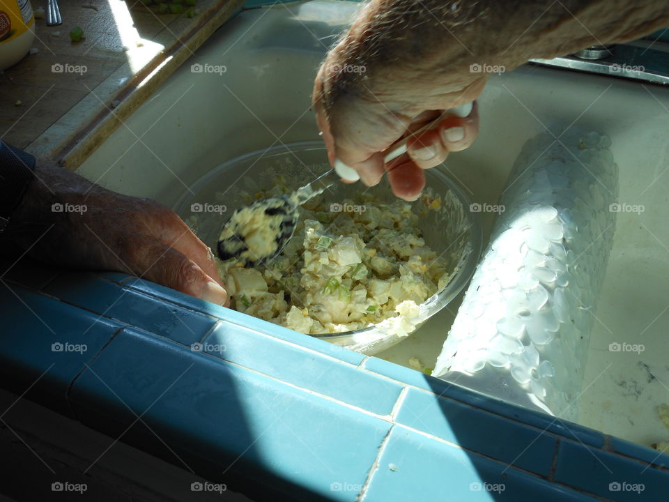 Hands working to make potato salad 